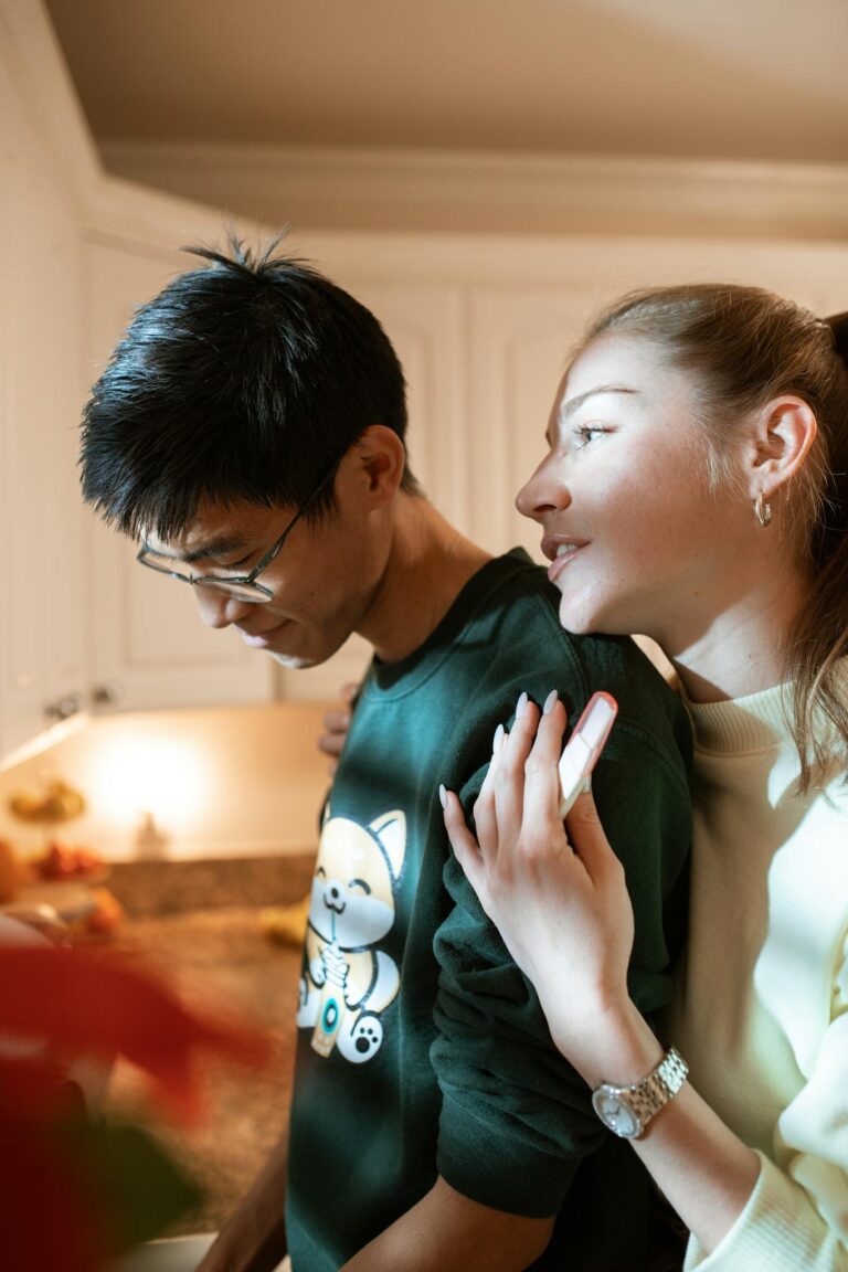 A couple shares a tender moment in a warmly lit kitchen, capturing love and togetherness.