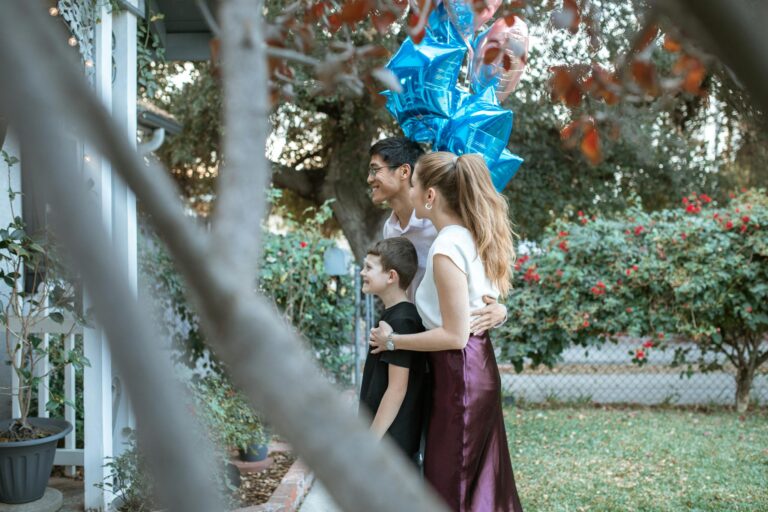 A happy family celebrates outdoors with vibrant blue balloons and joyful smiles.