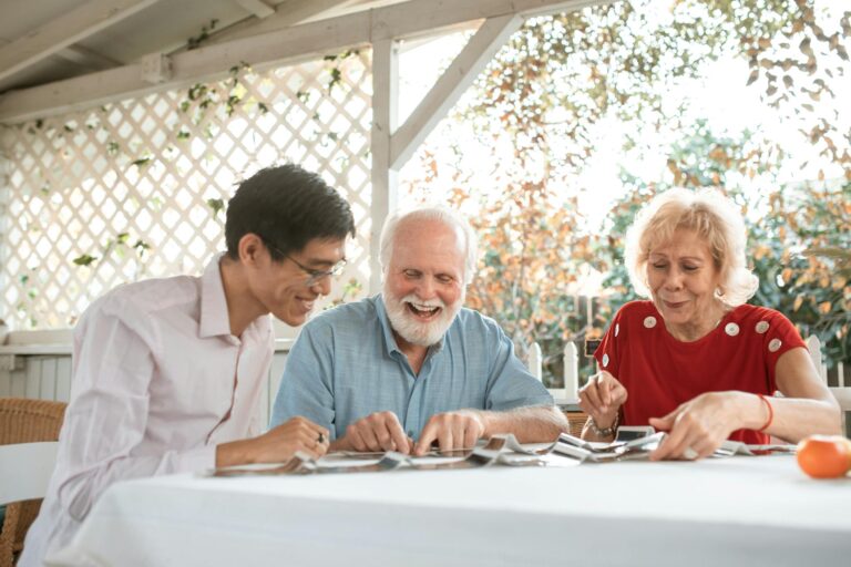 Three people enjoying a joyful moment with photographs outdoors in a cozy setting.